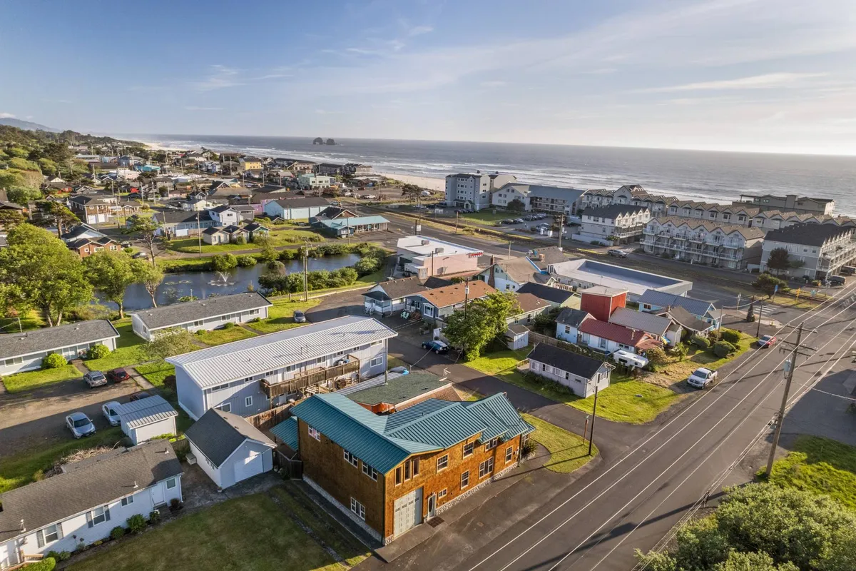 This image offers a wide coastal view featuring the neighborhood layout, a prominent building with a teal roof, the ocean in the background, and a sense of the vibrant, walkable community. Local shops and the proximity to the beach are suggested by the layout, providing both a glimpse of everyday life and the natural beauty just beyond.