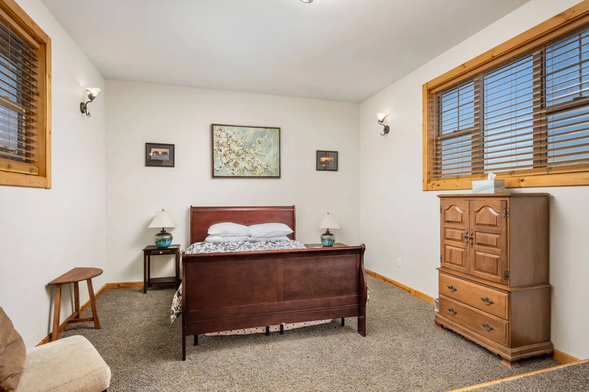 A peaceful bedroom with a queen-sized bed, art on the wall, nightstands, and a dresser. Soft light fills the room, enhancing the sense of comfort and tranquility—an ideal sanctuary for restful nights.