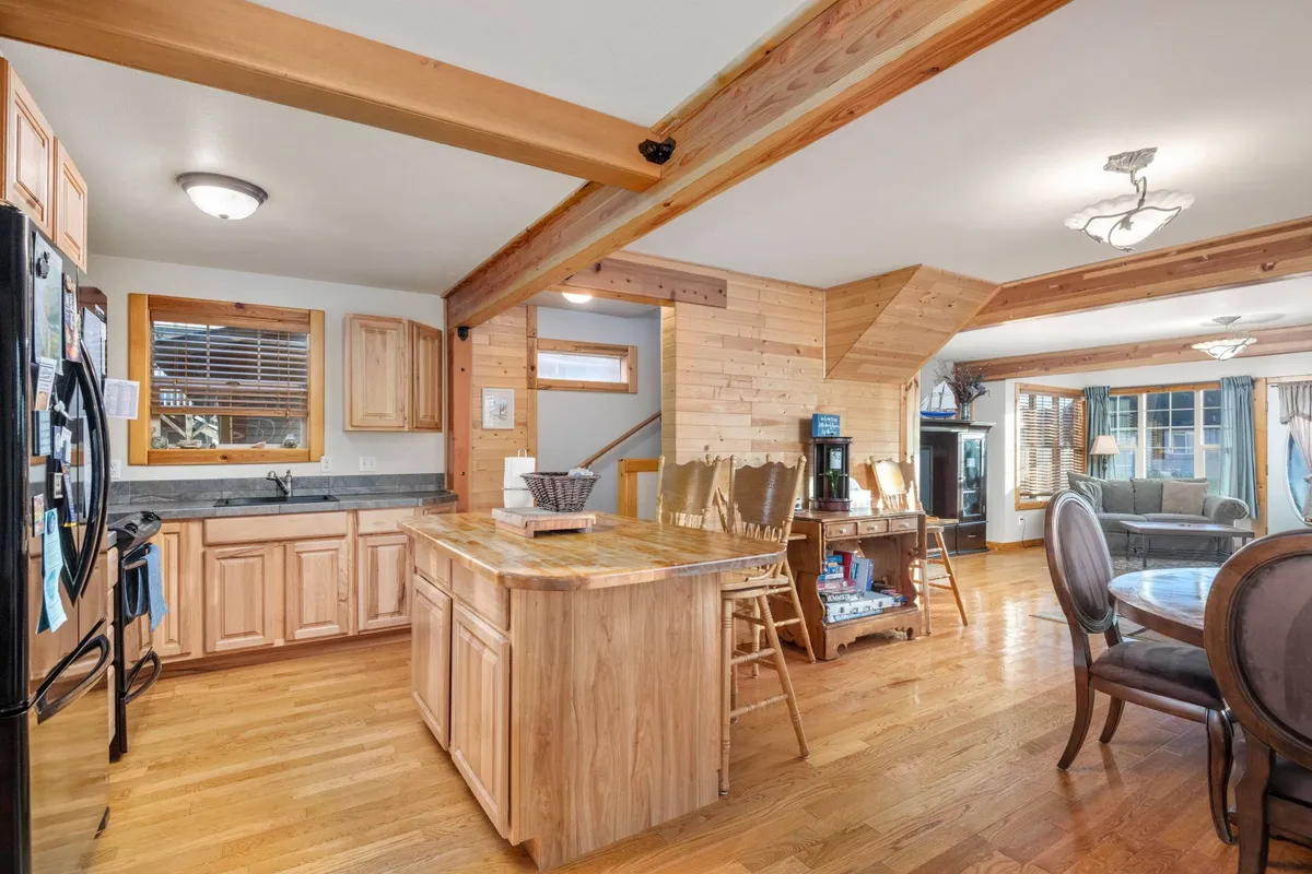 This image shows an inviting kitchen island with wooden cabinetry, seamlessly connected to a cozy dining area. The space is well-lit and arranged for gathering, cooking, and sharing meals, with ample room for family and friends to interact as meals are prepared and enjoyed.